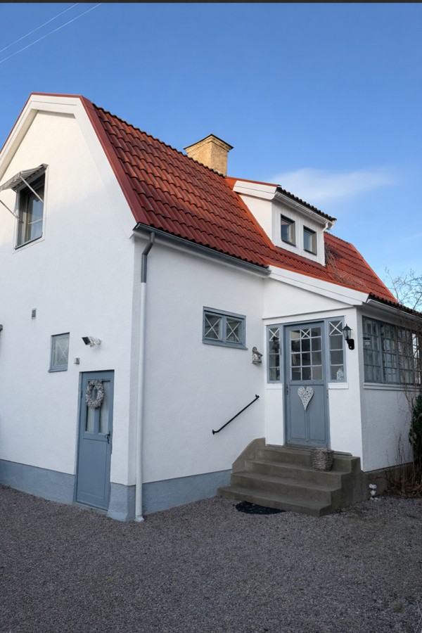 Det fristående gårdshuset med vit putsfasad och rött tegeltak